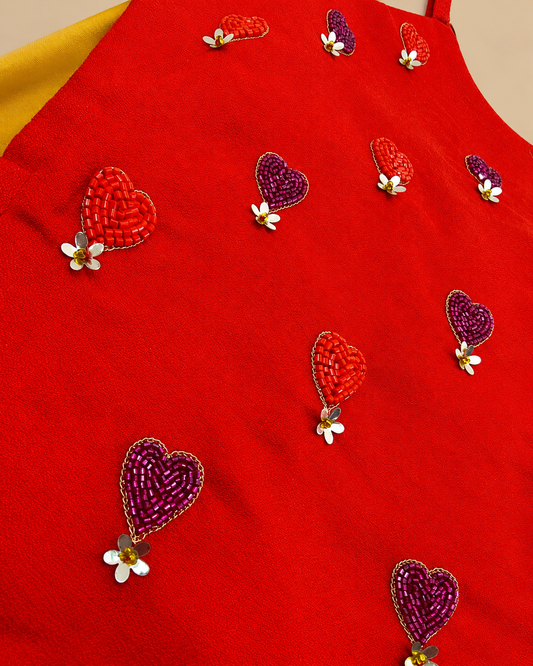 Girls' orange and yellow lehenga set with heart embroidery, pearl embellishments, flared skirt and purple dupatta with golden lace border.