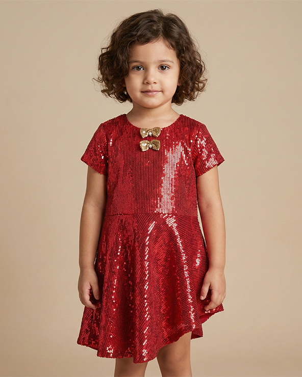 Girl wearing red poly sequin party dress with bow detail