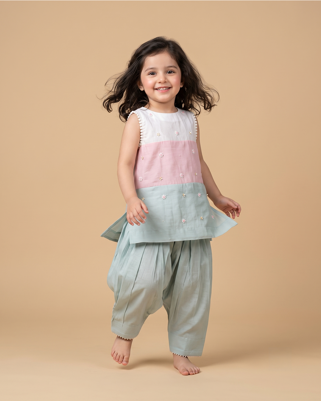Girl wearing a pastel Chanderi peplum kurta with floral embroidery and matching dhoti pants for festive occasions