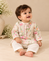 Baby boy wearing an ivory pure cotton floral kurta with pink placket embellishment and matching ivory bottoms.
