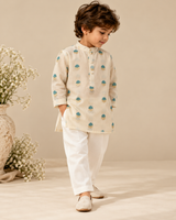 Boy wearing an ivory Chanderi kurta set with teal and gold zari floral motifs, pearl buttons and matching trousers.