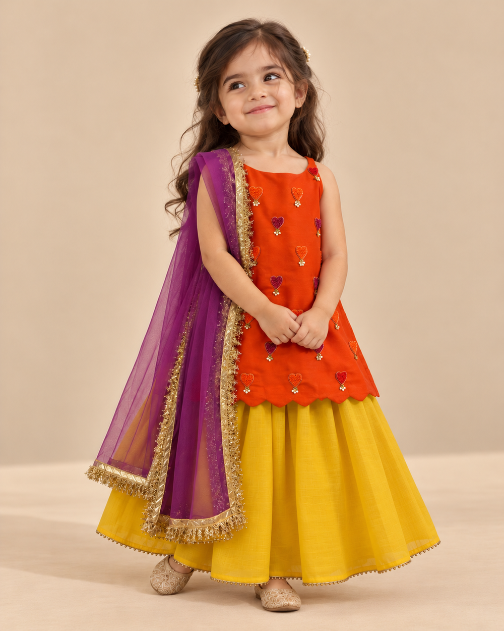 Girls' orange and yellow lehenga set with heart embroidery, pearl embellishments, flared skirt and purple dupatta with golden lace border.