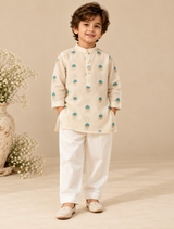Boy wearing an ivory Chanderi kurta set with teal and gold zari floral motifs, pearl buttons and matching trousers.